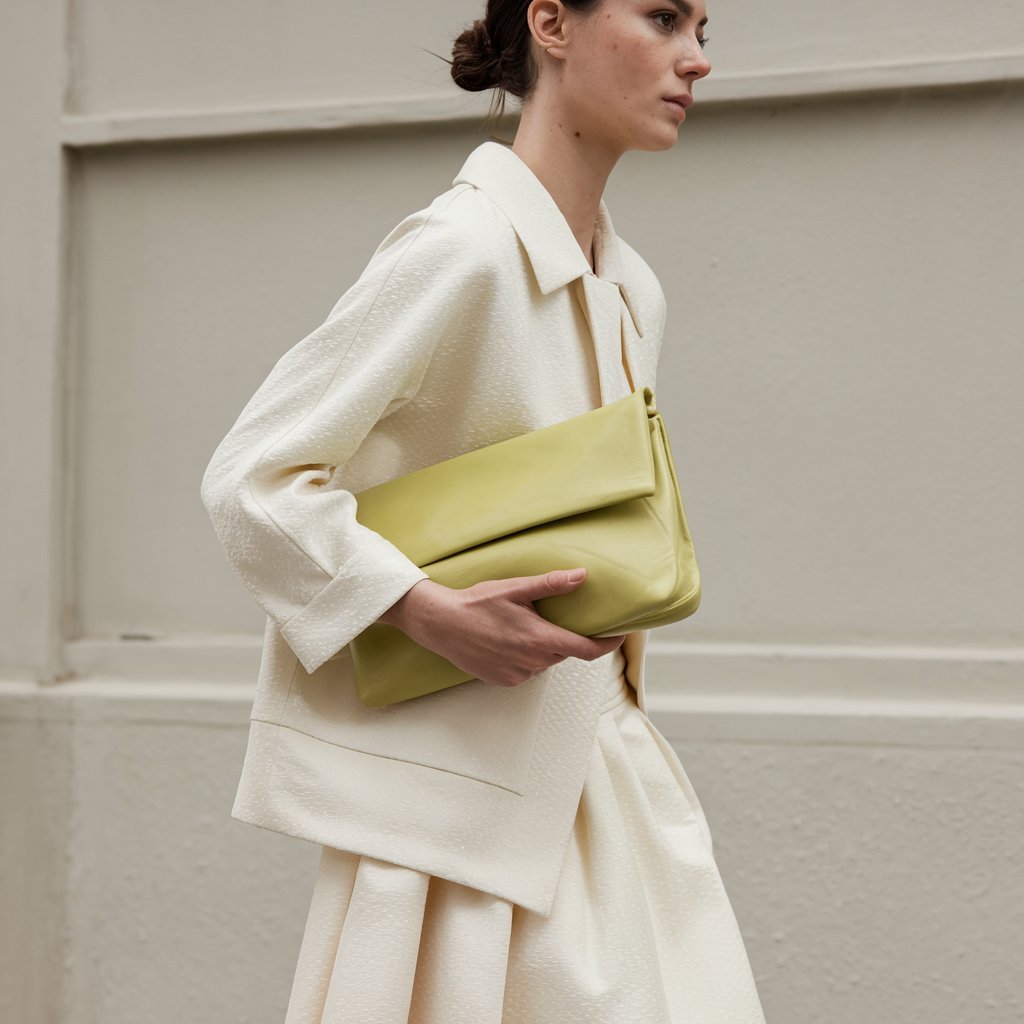 Person wearing a tonal spring outfit accessorized with a bold pop of color.